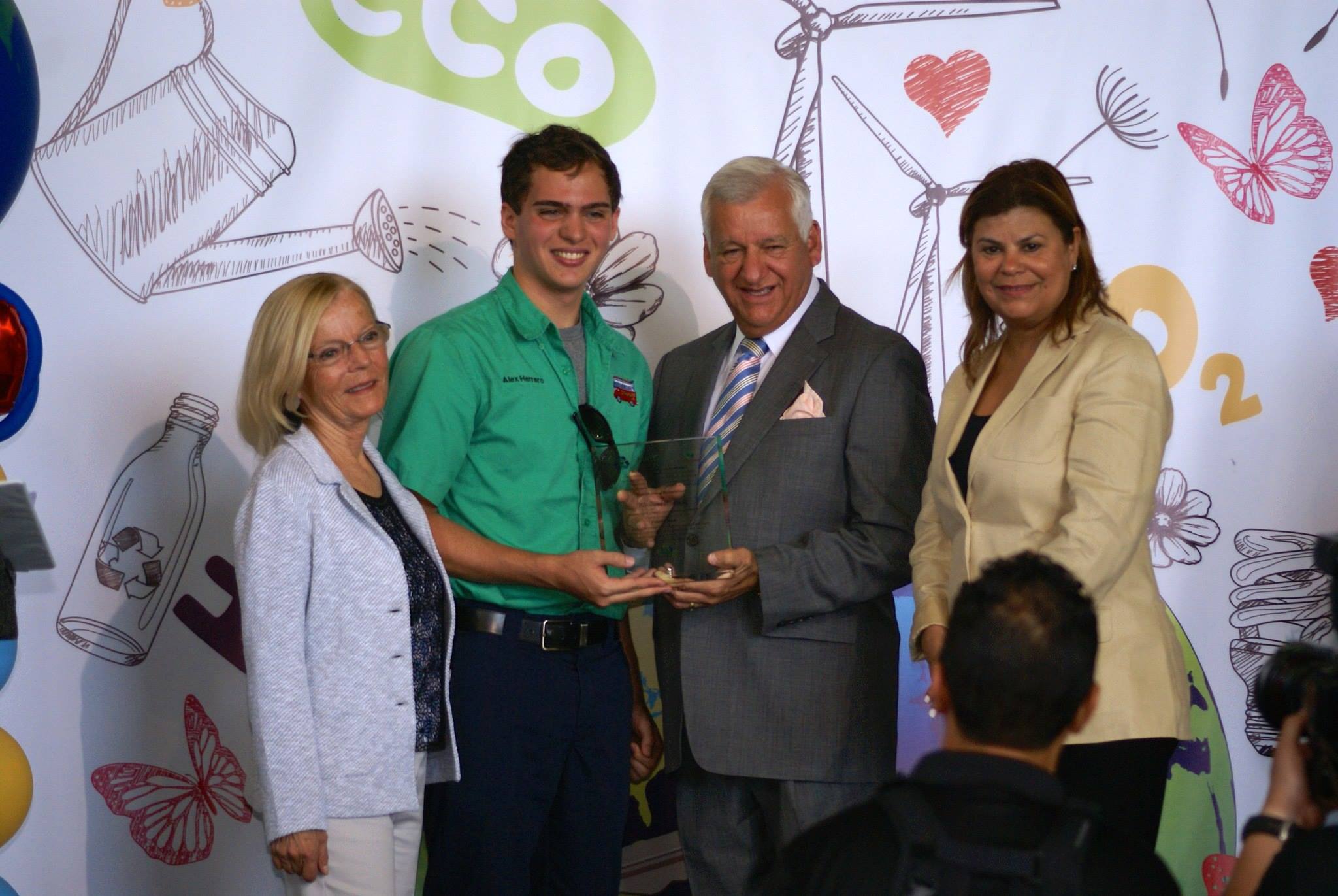 Receiving an environmental award on stage in a green Scout shirt, holding a glass trophy