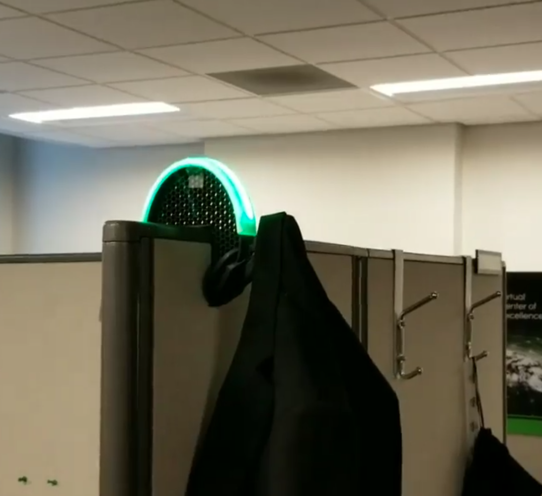 Final build mounted on a cubicle — a coat hanger with a status LED glowing green to signal availability